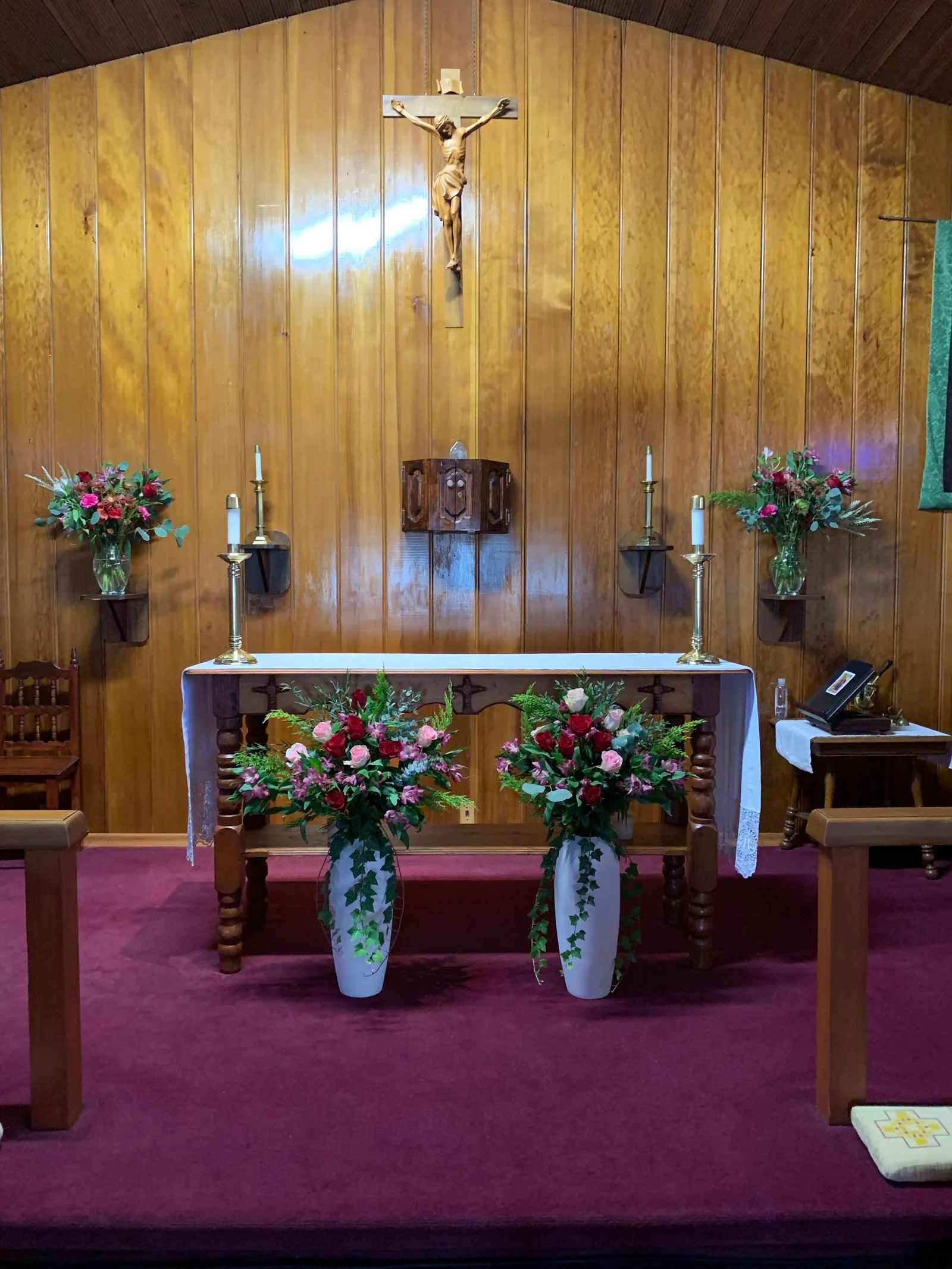 The altar, flowers, candles, and crucifix inside St. Michael - San Miguel.