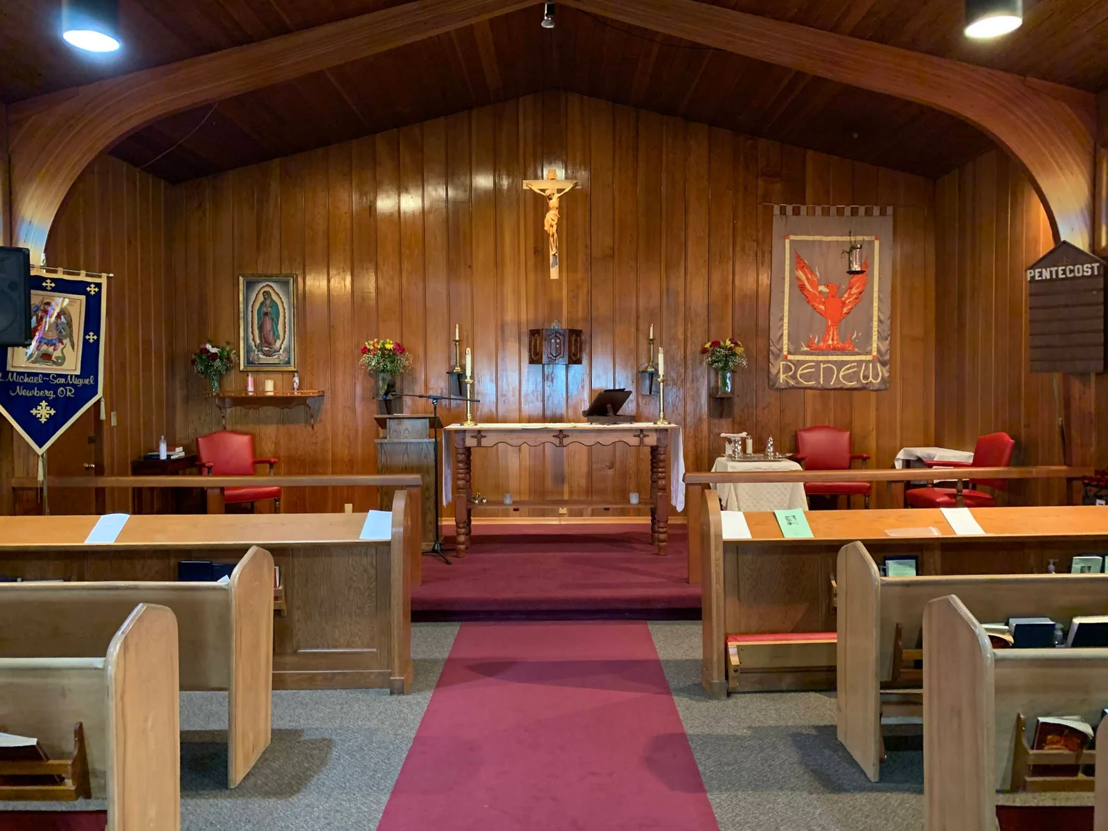 Wooden pews and a center aisle facing the altar inside St. Michael - San Miguel.