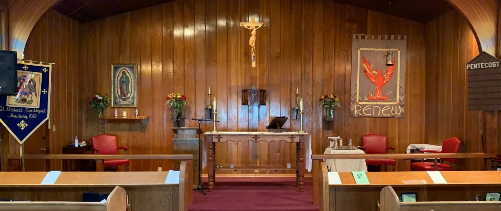 Wooden pews and a center aisle facing the altar inside St. Michael - San Miguel.